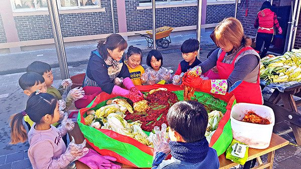 어린이들이 부모님과 김치를 담고 있다.