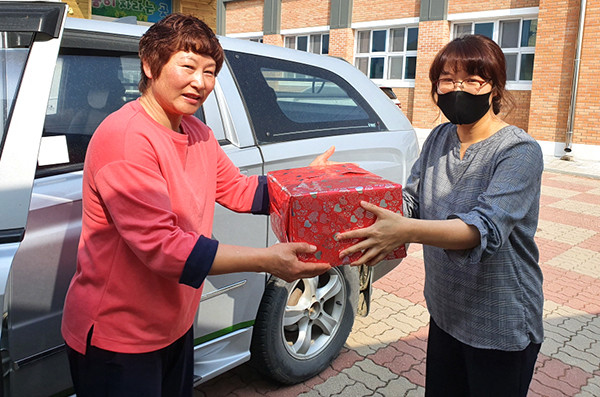 탄부초 교사가 학생 집을 찾아 어린이날 선물꾸러미를 학부모에게 전달하고 있다.