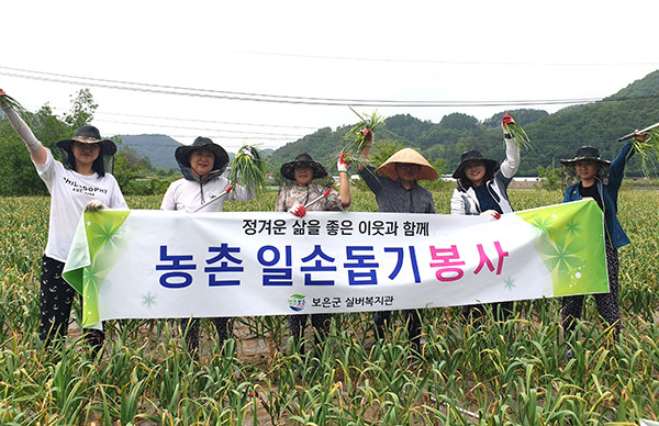 보은군실버복지관 직원들이 농가일소돕기에 나서 마늘 쫑(마늘주아)을 뽑아들고 풍년농사를 기원하고 있다.