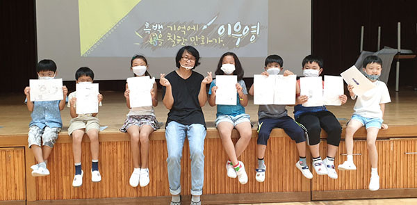 이우영작가로부터 지도를 받은 학생들이 함께 그린 만화를 들어 보이며 만족해하고 있다.