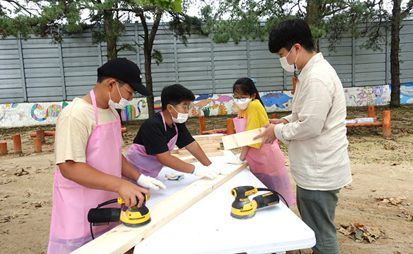 송죽초 학생들이 트리하우스를 짓기 위해 나무를 잘라 그라인더로 다듬고 있다.