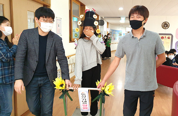 시 쓰기 대회애서 장원에 오른 박이솔 학생이 화관을 쓰고 선생님이 끌어주는 꽃수레에 올라 시상식장으로 들어서고 있다.