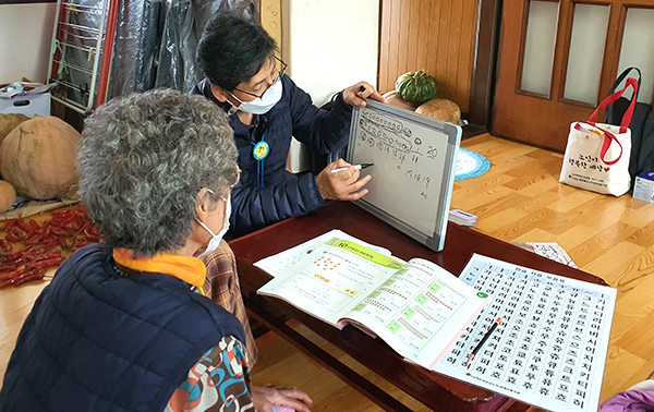 문해교실강사가 어르신집을 방문해 숫자와 한글을 가르치고 있다.