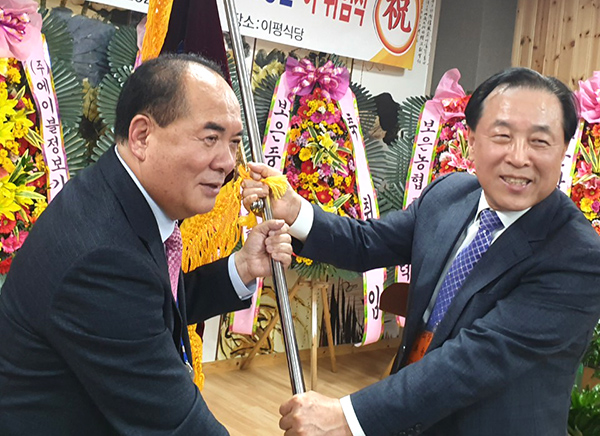 보은중학교 총동문회 이좌용 회장이 신임 성원제 회장에게 동문회기를 전달하고 있다.