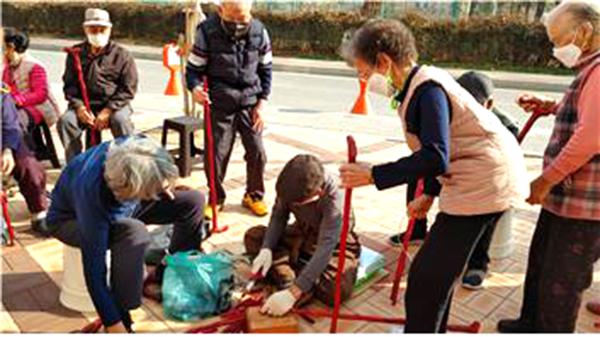 서재원 옹이 자신이 만든 지팡이를 다른 노인의 키에 맞추어 자르고 있다.