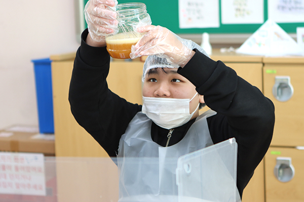 고추장을 만드는 학생이 메주가루의 양을 눈으로 살펴보고 있다.