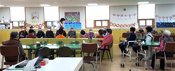 사회복지사가 노인주간보호센터 어르신들께 코로나 바이러스 방지방법에 대해 설명하고 있다.