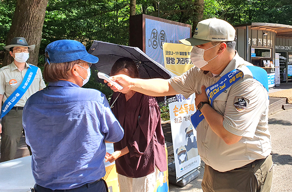 속리산국립공원사무소 관계자가 탐방객의 발열체크를 통해 코로나19 예방활동을 펼치고 있다.