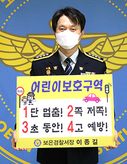 보은경찰서 이종길 서장이 ‘1단 멈춤, 2쪽 저쪽, 3초 동안, 4고 예방’이라는 슬로건이 담겨있는 판넬을 들고 어린이 교통안전 릴레이 챌린지에 동참하고 있다.