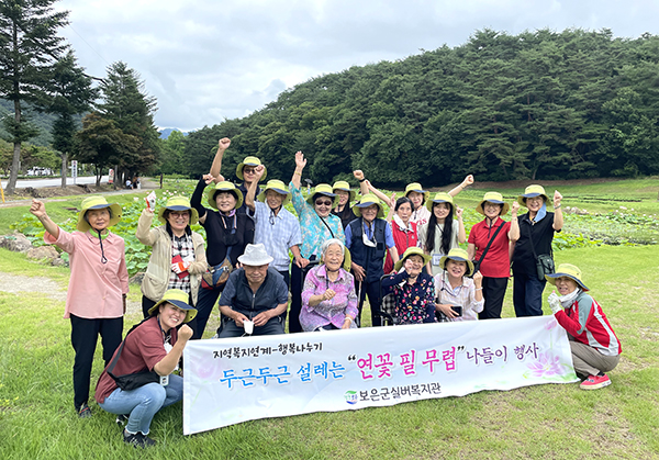 실버복지관 어르신들이 연꽃핀 연못앞에서 즐거움의 환호를 터트리고 있다.