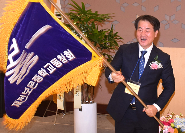 신임 주홍건 회장이 직전 조봉수 회장으로부터 전달받은 동문회기를 흔들고 있다.