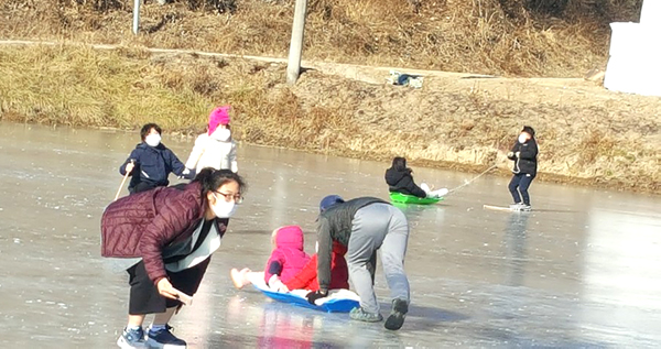 얼음썰매장에서 아이들과 주민들이 썰매 타는 재미에 흠뻑 빠져 있다.