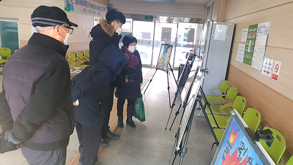 시외버스터미널을 지나는 군민들이 전시되어있는 불조심 포스터를 살펴보고 있다.