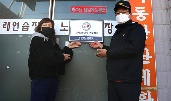 보은소방서가 보은노래연습장을 방문해 소방 안전관리 우수업소 인증표지를 부착하고 있다.