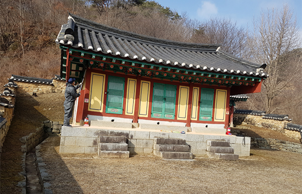 후율사를 찾은 문화재돌보미가 건물 구석구석에 걸린 거미줄을 제거하고 있다.