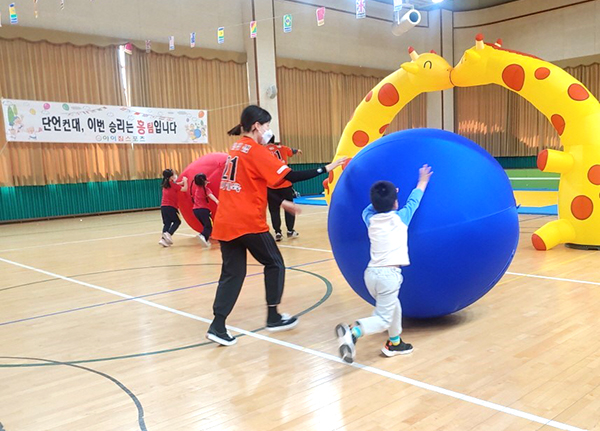유치원 유아들이 지구를 굴리고 있다.