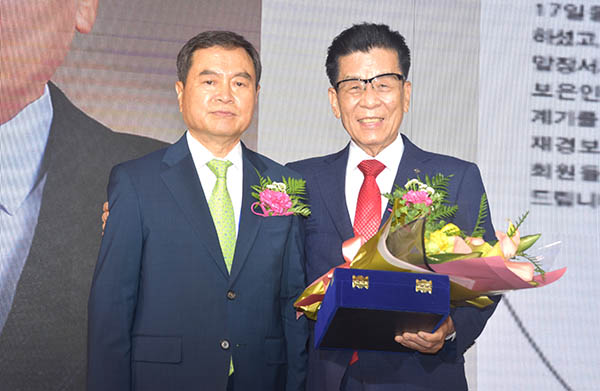 황인학 신임회장이 이임하는 정영기 회장에게 꽃다발을 선사하며 감사를 표하고 있다.