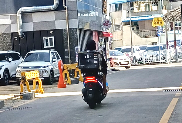 한 음식점 배달원이 번호판이 없는 오토바이를 타고 버젖이 운행하고 있다.