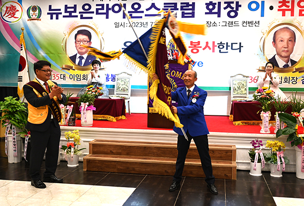 취임하는 김형태(우)회장이 이임하는 김홍봉 회장(좌)으로 부터 받은 뉴-보은라이온기를 힘차게 흔들고 있다.