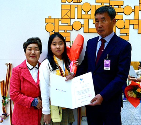 재외동포 어린이 한국어 그림일기 대회에서 우수상을 수상한 류수정 어린이가 할아버지 할머니와 이를 기념하고 있다.