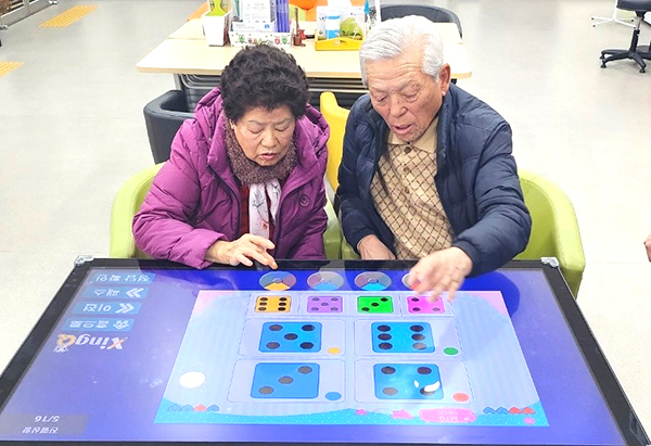 노인들이 멀티미디어 학습장치를 이용해 인지테스트를 하고 있다.