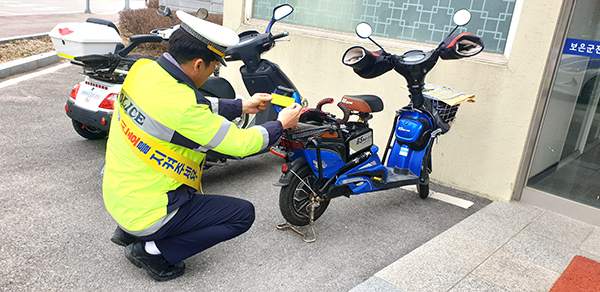 보은경찰서 경찰관이 주민의 교통사고 예방을 위해 오토바이에 고휘도반사지를 붙이고 있다.