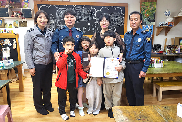 지화영(뒷줄 사복)씨가 아이들과 함께 김현우 서장으로부터 감사장을 받고 있다.