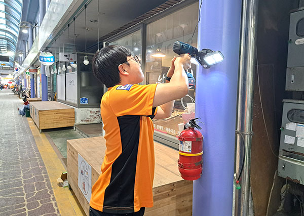 보은소방서 소방관이 보은전통시장에 태양광 LED센서등을 설치하고 있다.