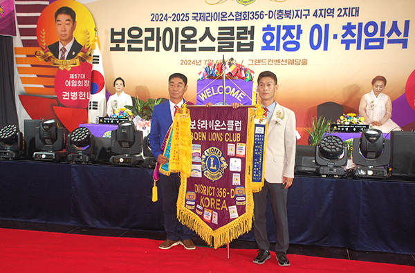 권병헌 회장이 김송기 신임회장에게 라이온기를 전달하고 있다.