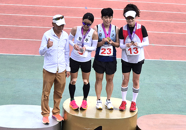 육상 여자부 400M에서 3위를 차지한 하유정 선수가 시상대에 올라 목에 메달을 걸고 있다.