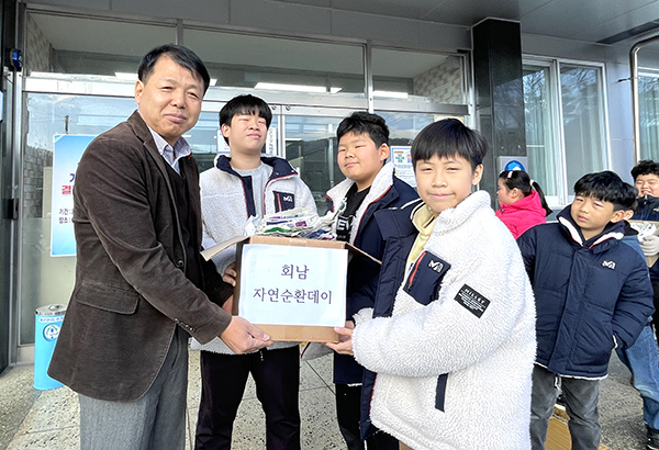 홍영의 회남면장이 빈 우유팩을 모아온 학생들에게 종량제 쓰레기봉투를 전달하고 있다.