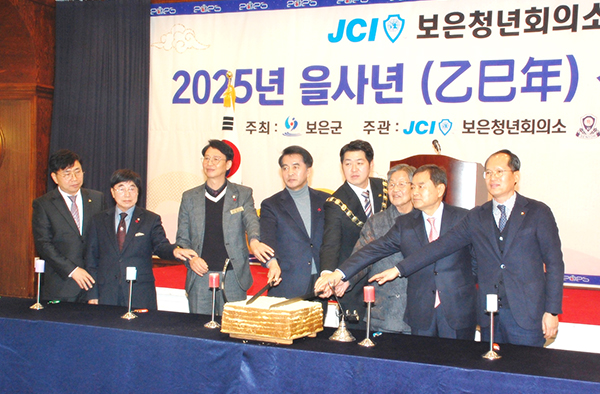 보은청년회의소가 주최한 2025년 신년인사회에서 노해선 회장과 최재형 군수를 비롯한 기관단체장들이 보은발전을 기원하는 떡을 자르고 있다.