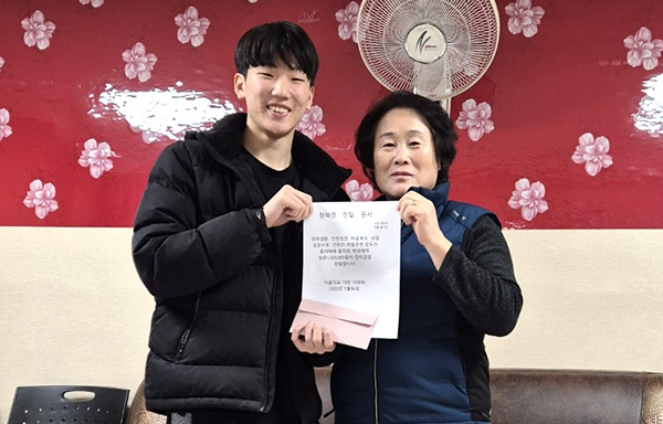 이명희 건천리 이장이 홍지민 군에게 장학금을 전달하고 있다.