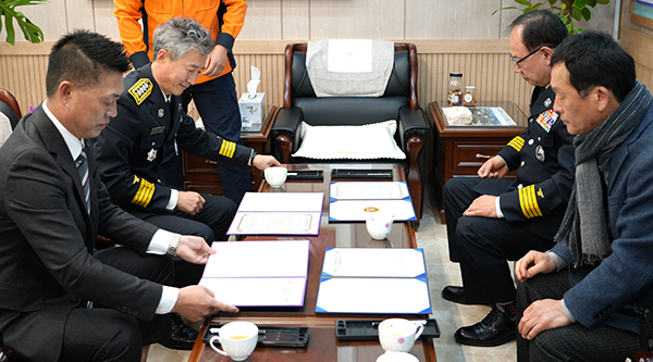 강문수 보은소방서의용소방대장과 허수훈 서귀포소방서의용소방대장 허수훈이 양측 소방서장이 지켜보는 가운데 업무협약서에 서명하고 있다.