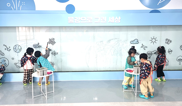 어린이집 원아들이 유아교육진흥원 마음키움터 벽면에 물감으로 그림을 그리고 있다.