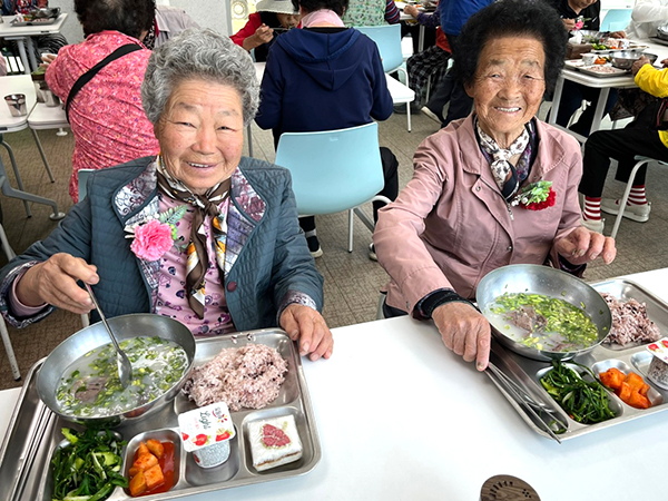대청댐노인복지관에서 준비한 미나리곰탕을 받은 어르신들이 환한 미소를 띄우고 있다.