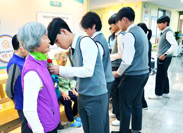 보은중 학생들이 보은군실버복지관을 찾아 어르신들 가슴에 카네이션을 달아드리고 있다.