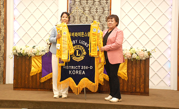 김연실 보은루비라이온스클럽 이임 회장이 신임 김정숙 회장에게 기를 전달하고 있다.