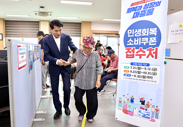 소비쿠폰 지원사업이 시작된 21일 최재형 군수가 도우미로 나서 소비쿠폰을 신청하러온 주민을 반갑게 맞이하고 있다. /제공 보은군