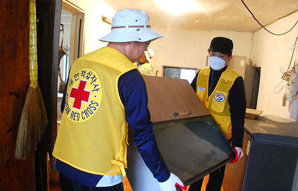 연송적십자 봉사원들이 집수리를 하기 위해 물품을 밖으로 빼내고 있다.
