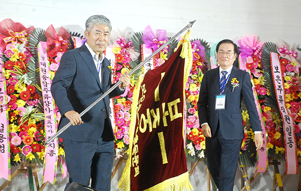 이태영 이임회장이 한창환 신임회장에게 총동문회기를 전달하고 있다.