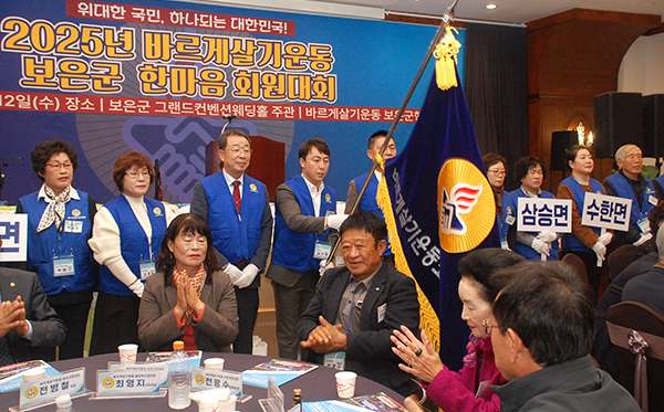 바르게살기운동보은군협의회 임원들이 기를 들고 인사하고 있다.