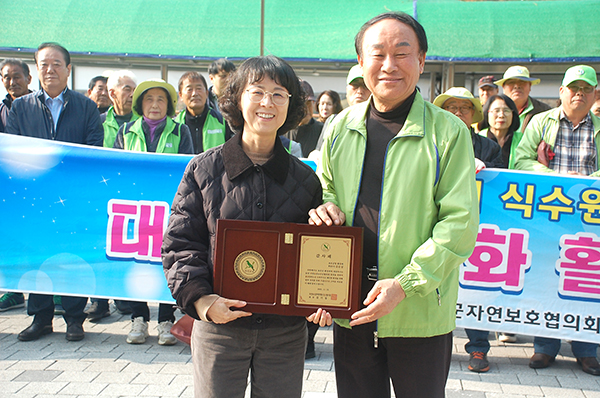 김기동 보은군자연보호협의회장이 환경위생과 김순섭 주사에게 감사패를 전달하고 있다.